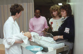 Photograph of an instructor teaching students how to care for a newborn baby using a doll