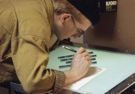 Photograph of a Photography student inspecting negatives on light table