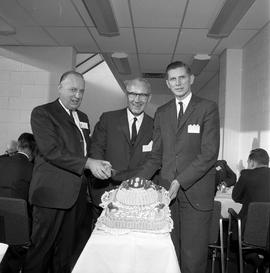 Photograph of staff members cutting a celebration cake inside the D building