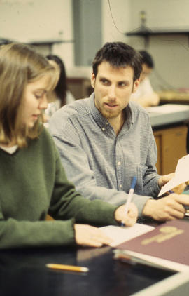 A photograph of students in class conversing over their notes