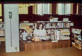 Photograph of Suzanne Swalm Sitting on her Desk in the Lakeshore Library
