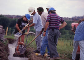 Photograph of groundskeepers working on a retaining wall