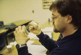 A photograph of Landscape program student examining jars of seeds