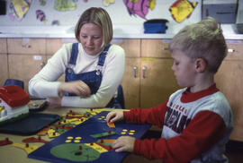Photograph of an early childhood educator and a child seated at a table