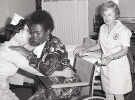 Photograph of a nurses supporting a wheel chair patient