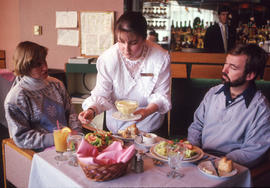 Photograph of a student in the Hospitality program serving staff members in the Humber Room