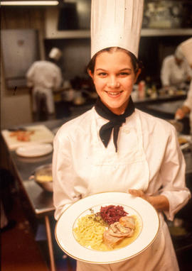 Photograph of a culinary student posing with her finished plate