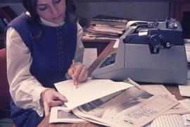 Student or staff member looking at text and newspapers : [photograph]