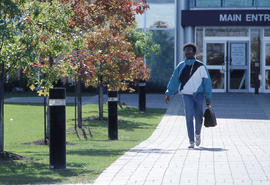 Photograph of a student walking by the main entrance of NX building