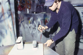 A photograph of an Industrial Design student spray painting his design