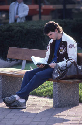 Photograph of a student reading outside on a bench