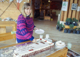 Photograph of Christine Fraser cutting cake for Earth Day in the Arboretum