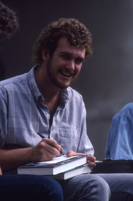 Photograph of student writing notes while smoking