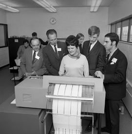 Photograph of visitors watching a printer operation in the D-building computer room