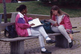 Photograph of Two Students Talking on a Bench Outside