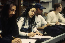Photograph of students sitting in an unknown classroom taking notes