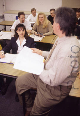 Photograph of a relaxed instructor teaching in a classroom at an unknown location