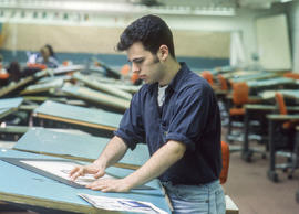 Photograph of a student in the Graphic Design program at a drafting table