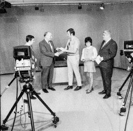 Photograph of Gordon Wragg being filmed presenting awards to various students