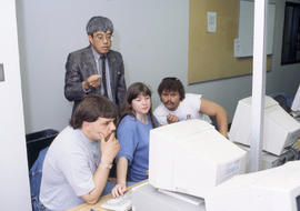 Photograph of an instructor working with students in a computer lab