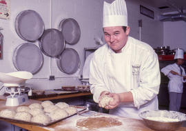 Photograph of a culinary student filling a tray with balls of dough to make bread