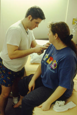 Photograph of a nursing student performing a procedure on another student in the lab