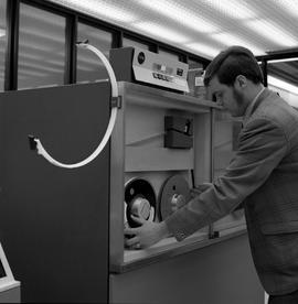 Photograph of a student computer operator mounting a digital magnetic tape on a trap drive