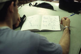 A photograph of an Industrial Design student making sketches in his notebook