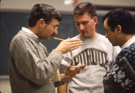 Photograph of a faculty member (on the left) talking with students