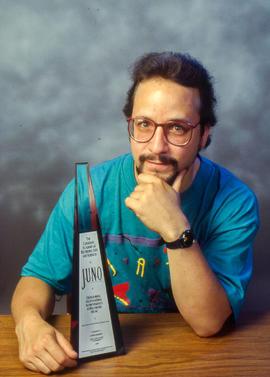 Photograph of Brian Dickenson next to the JUNO award he won
