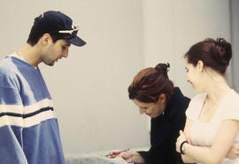 A photograph of three students in discussion over notes