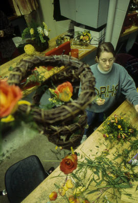 A photograph of a Retail Floriculture student assembling a floral arrangement