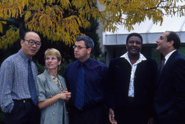 Photograph of staff standing under a tree