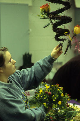 A photograph of a Retail Floriculture student building an arrangement