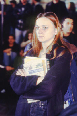 Photograph of a student holding a textbook and the Toronto Star