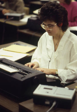 Photograph of a student at a typewriter transcribing from a Dictaphone machine