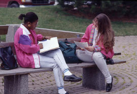 Photograph of Two Students Talking on a Bench Outside